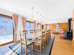 Ein geräumiger Raum mit einem großen Holzesstisch, mehreren Stühlen, einer Couch und einem Kamin.