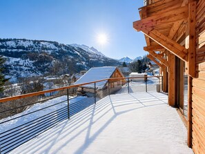 A wooden cabin with a balcony overlooking a snowy mountain landscape.