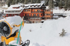 A snow-covered landscape with a multi-story building featuring balconies and a ski lift in the foreground. - Hotel Al Foiron (Claviere)