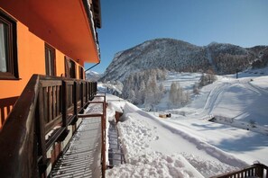 A snow-covered mountain landscape with a building featuring a balcony. - Hotel Al Foiron (Claviere)