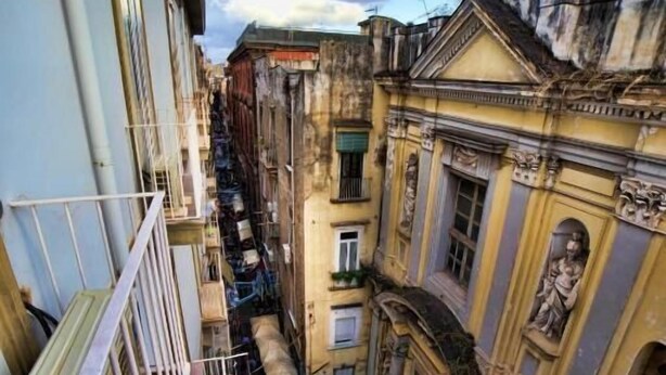 A narrow street with buildings on either side, balconies, and a clear sky. - Sciuscià beb spaccanapoli (Naples)