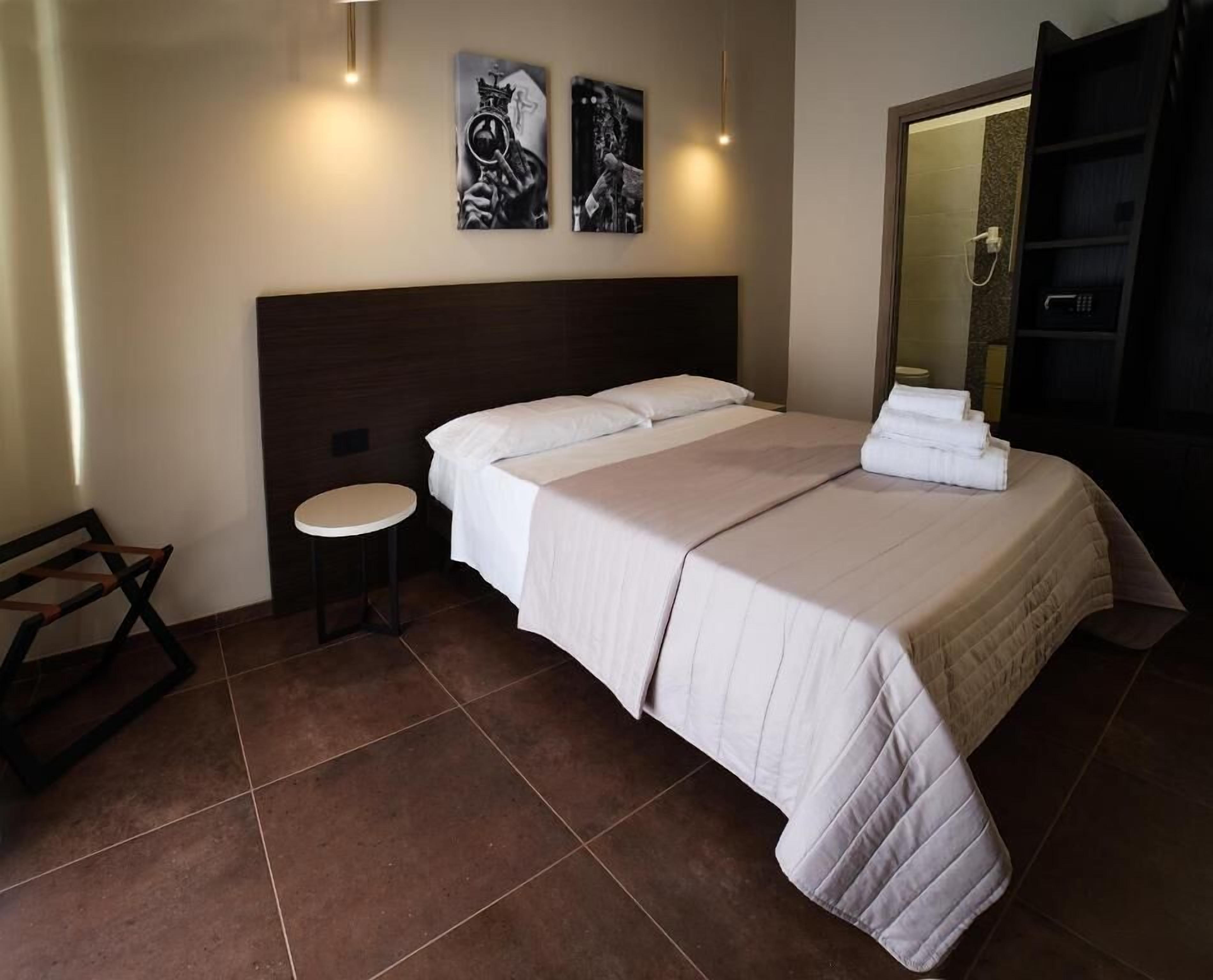 A hotel room with a large bed, a small round table, a mirror, and artwork on the wall.