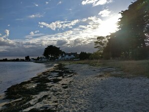 A beach with a house in the background, a clear sky, and sunlight. - Family Home from 1806: Between Land and Sea (Le Tour-du-Parc)