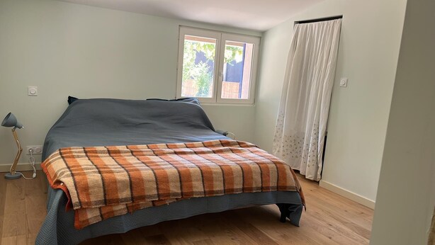 Una camera da letto con un letto, una finestra, una tenda e una lampada.