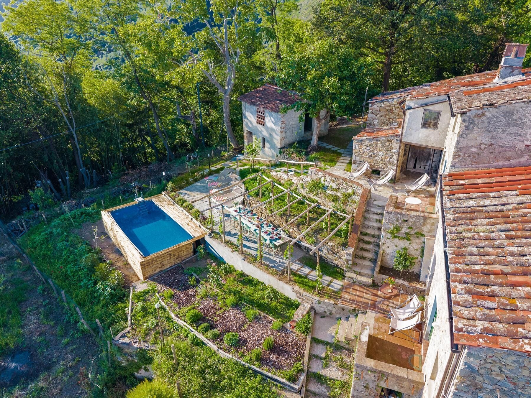 A rooftop garden with a swimming pool, outdoor seating, and a stone structure.