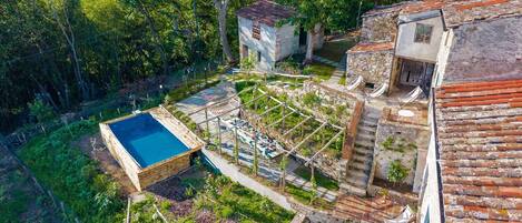 A rooftop garden with a swimming pool, outdoor seating, and a stone structure.