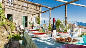 An outdoor dining setup with a stone building in the background, a table set with plates, glasses, and a bottle of wine. - Podere il Leccio with a Pool (LUCCA)