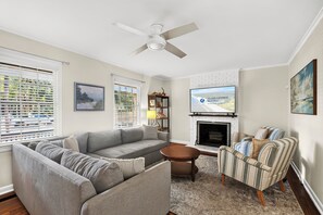 A living room with a grey sofa, striped armchair, and a fireplace. - 10 Myrtle Lane - South Forest Beach! (Hilton Head)