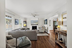 Ein Wohnzimmer mit einer Couch, Sesseln, einem Kamin und einem Essbereich mit Tisch und Stühlen.