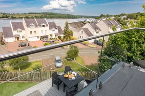 Een balkon met een ontbijttafel, met uitzicht op een woongebied met huizen en een waterpartij.
