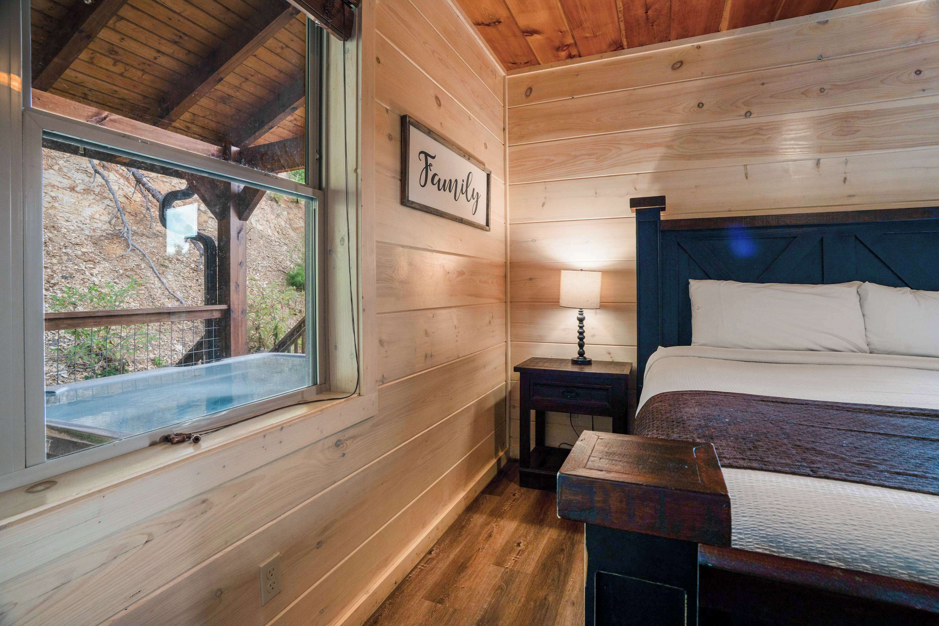 A wooden cabin bedroom with a bed, nightstand, and window.
