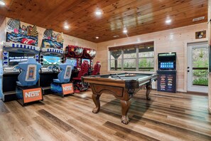A wooden-floored room with a pool table, arcade games, and a Legends Ultimate gaming machine. - Pigeon Forge Cabin Sleeps 76 | Hot Tubs, Arcade & Near Dollywood (Pigeon Forge)