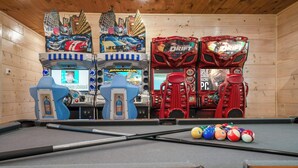 Ein Billardtisch mit Spielstock, umgeben von Spielautomaten, darunter BrawlHalla und Drift.