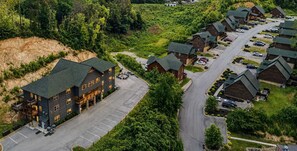 A lodge with multiple buildings, a parking lot, and a road leading to a wooded area. - Pigeon Forge Cabin Sleeps 76 | Hot Tubs, Arcade & Near Dollywood (Pigeon Forge)