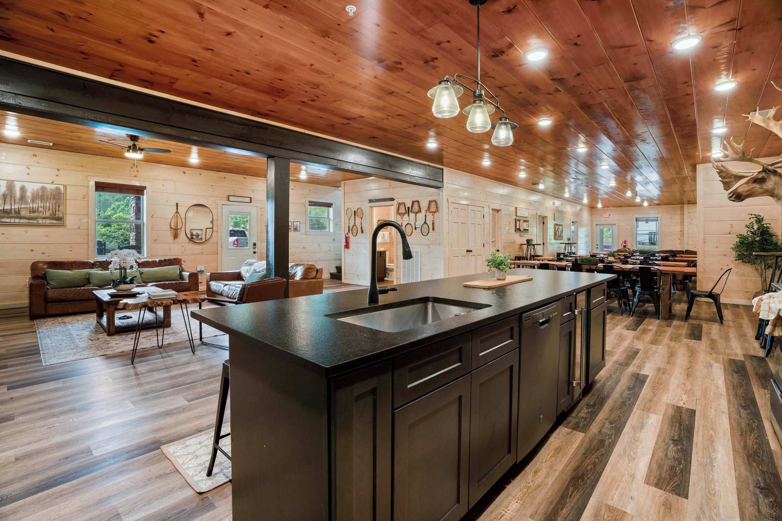 A spacious kitchen with a central island, wooden flooring, and pendant lighting.