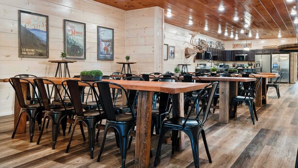 Ein Restaurant mit Holztischen und -stühlen, einer Küchenzeile und Postern an den Wänden.
