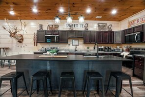 Kitchen island with seating for a crowd at Rocky Top Lodge, plus multiple coffee makers and toasters, so breakfast for 76 guests moves quickly before a Dollywood day 1.5 miles away. - Pigeon Forge Cabin Sleeps 76 | Hot Tubs, Arcade & Near Dollywood (Pigeon Forge)
