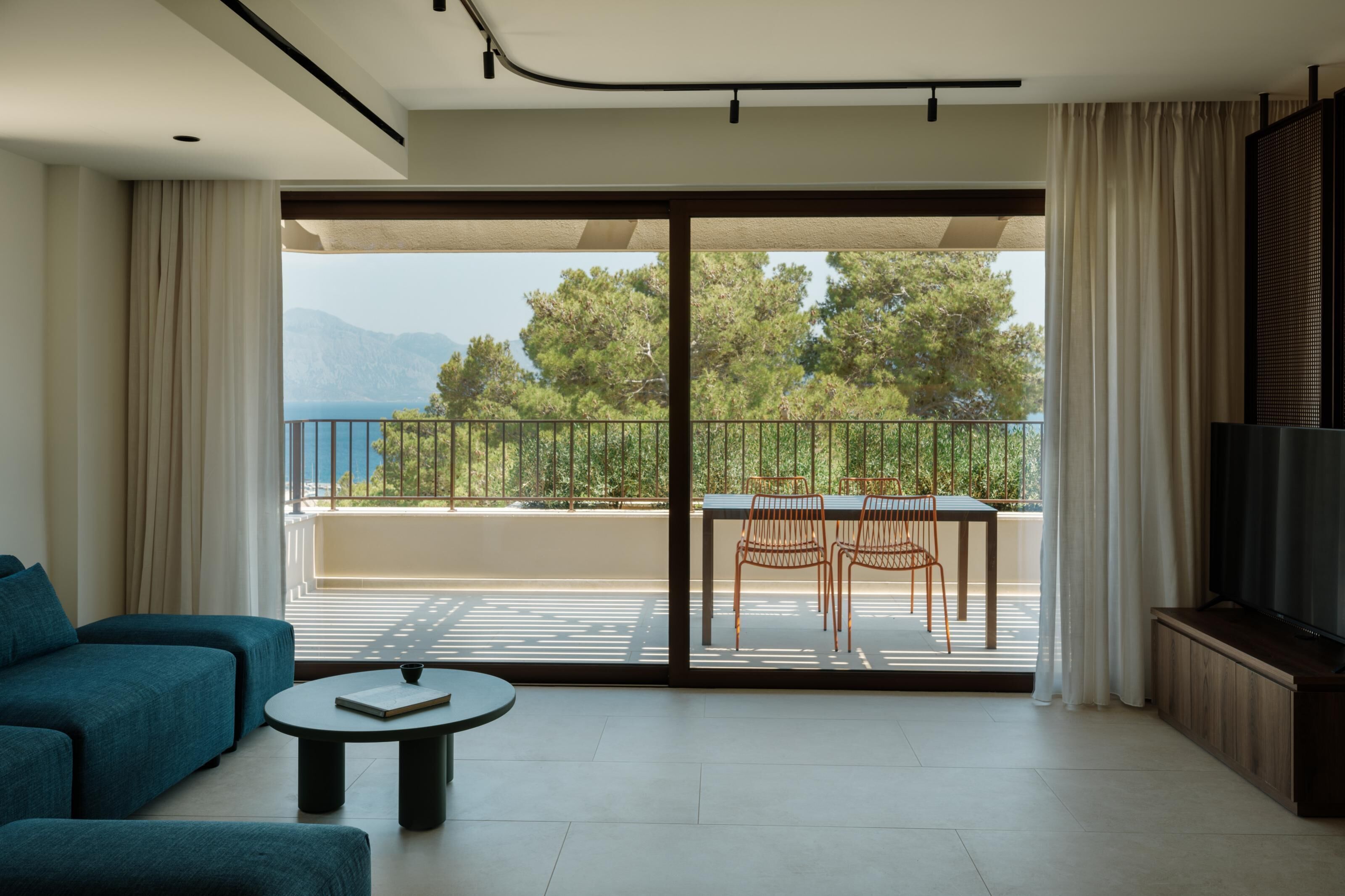 A modern living room with a sofa, a coffee table, and a balcony with a table and chairs.