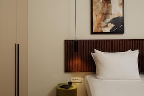 Ein Hotelzimmer mit Bett, Nachttisch, Wandbild und Holz-Kopfteil.
