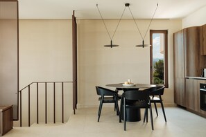 Eine moderne Küche mit Essbereich, ausgestattet mit einem runden Tisch und Stühlen, einem Einbauofen und Blick ins Freie.