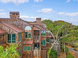 Une maison en bois à plusieurs étages, dotée de grandes fenêtres et d’un balcon.