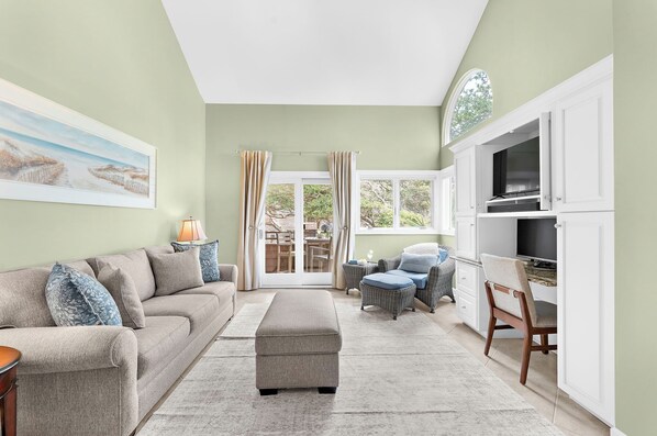 A living room with a sofa, ottoman, and a dining area with chairs and a table.