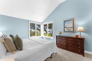 A bedroom with a bed, a dresser, a lamp, and a painting.