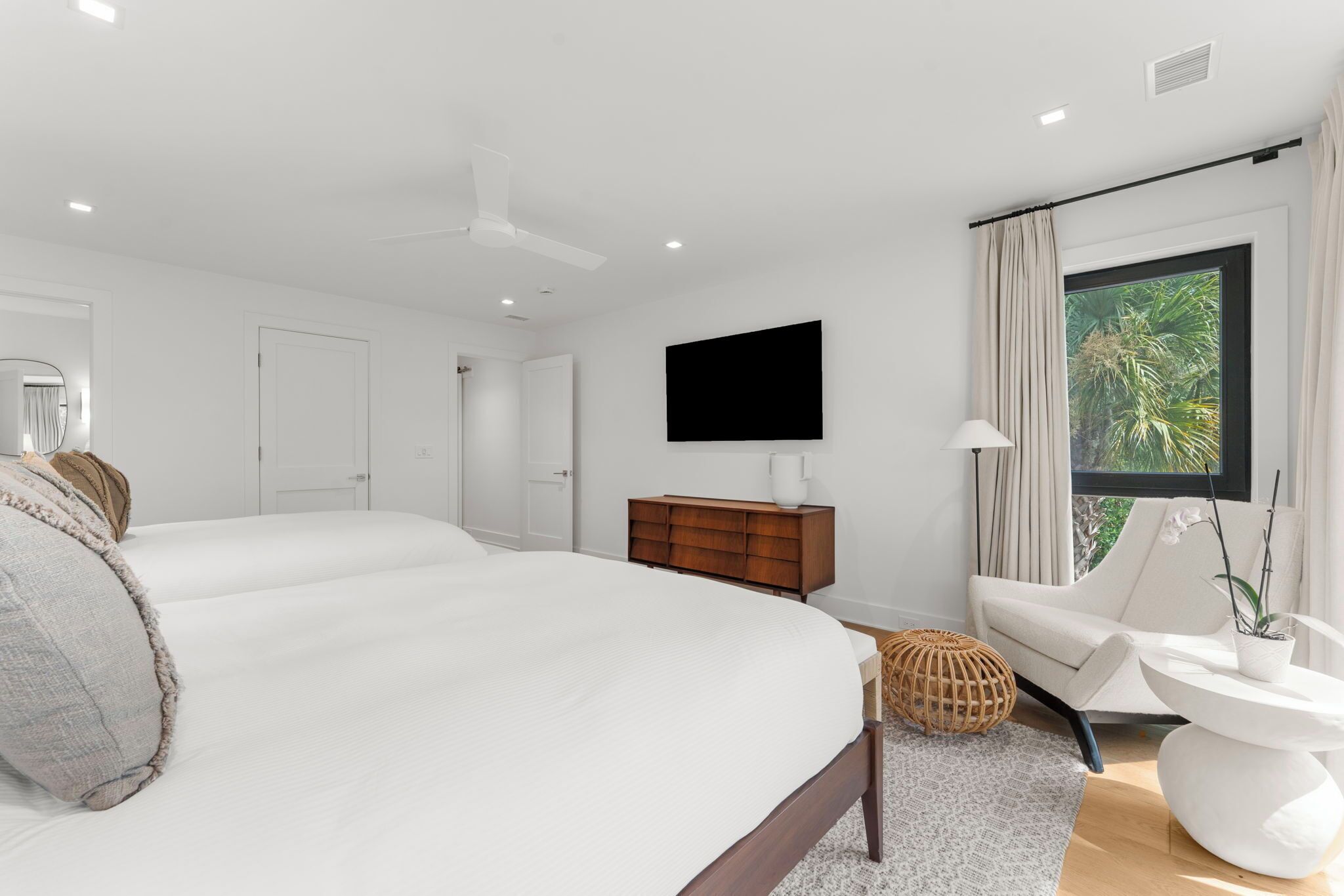 Une chambre moderne avec un grand lit, une commode en bois, une télévision et une fenêtre avec des rideaux.