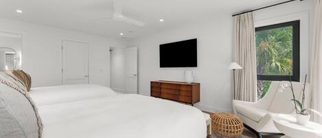 Une chambre moderne avec un grand lit, une commode en bois, une télévision et une fenêtre avec des rideaux.