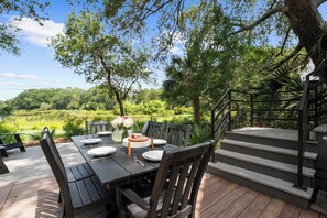 An outdoor dining area with a table set for four, surrounded by chairs, and a staircase leading to an upper level. - 333 Victory Bay : 4  BR, 4.5  BA House in Kiawah Island , Sleeps 10 (Kiawah Island)