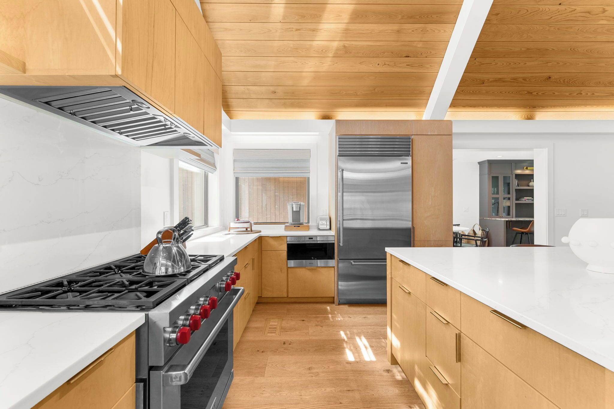 A modern kitchen with wooden cabinets, a stainless steel refrigerator, and a gas stove.