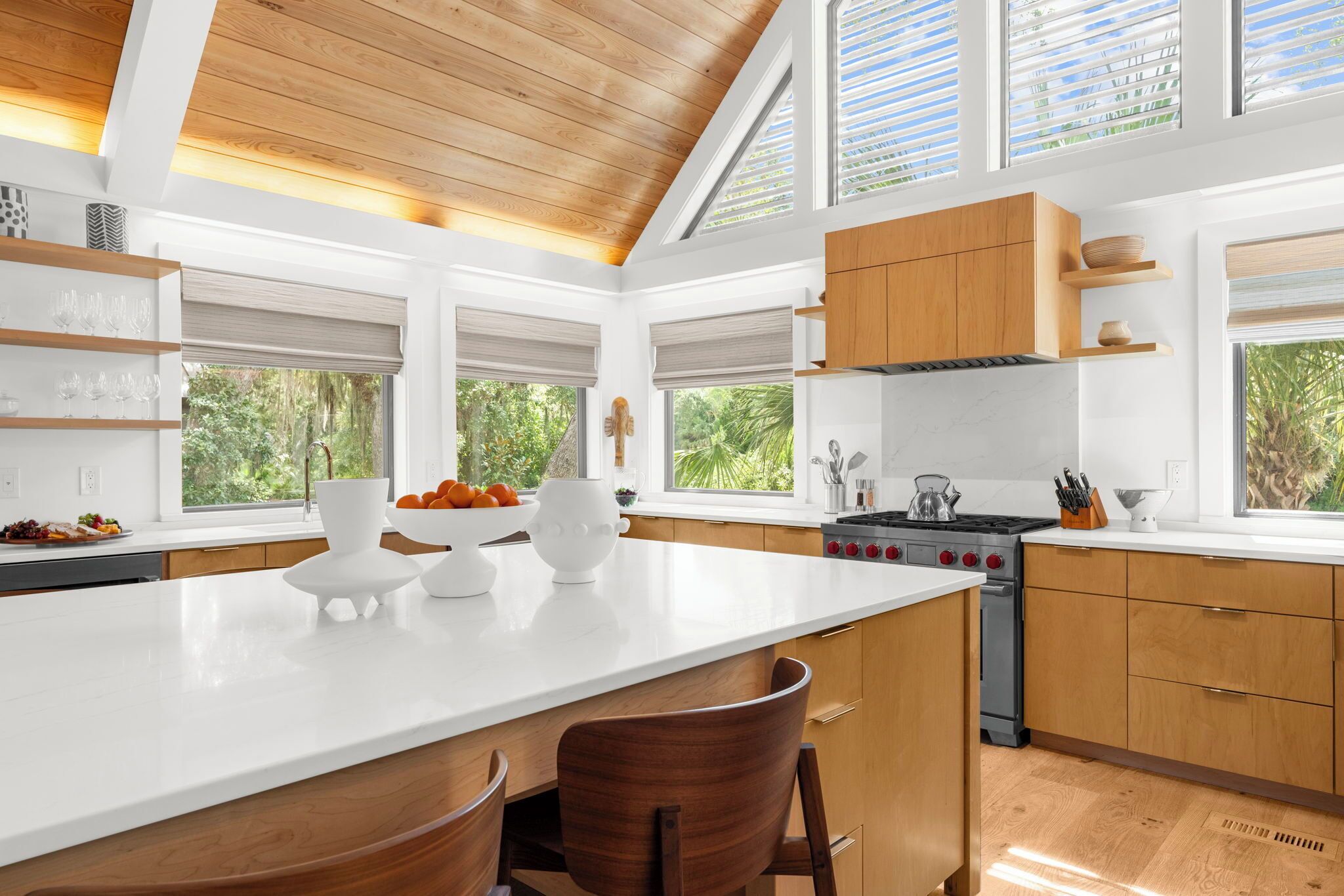 Una cocina moderna con una isla grande, armarios de madera y vista a zonas verdes.