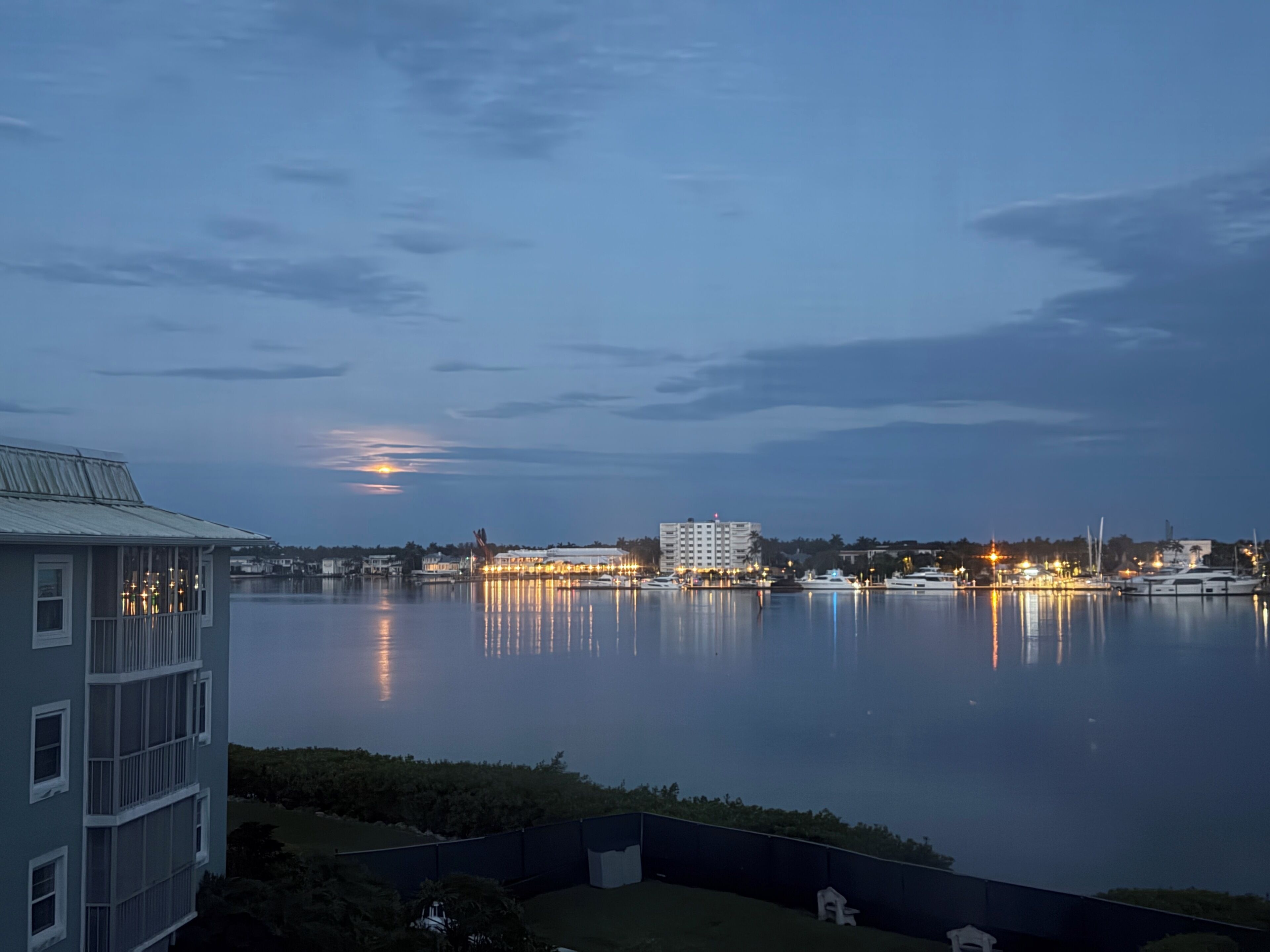 A waterfront view with buildings, a calm body of water, and a clear sky.