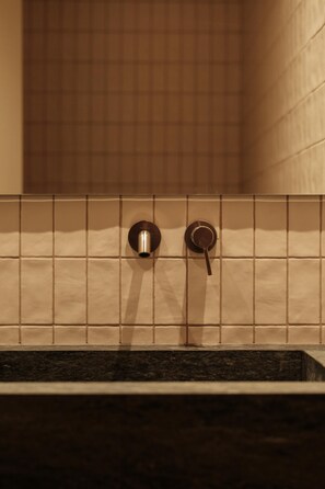 Une salle de bain avec un mur carrelé et un lavabo avec un robinet.