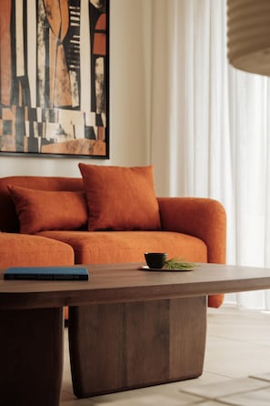 A modern living room with a sofa, a coffee table, and a book. - Linum Hill Apt Panoramic Sea View Sleeps 5 (Agios Nikolaos)
