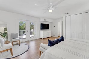 Une chambre à coucher avec un lit, une commode, une télévision et un balcon.