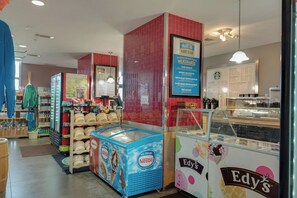 A cafe interior with a menu board, ice cream display, and a variety of seating options. - Beachfront Bliss with Gulf Views and Resort Pools (Panama City Beach)