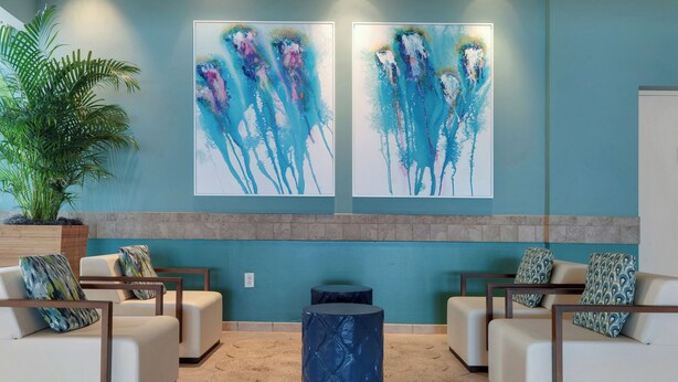 A lobby with two white sofas, a blue accent wall, and abstract art. - Beachfront Bliss with Gulf Views and Resort Pools (Panama City Beach)