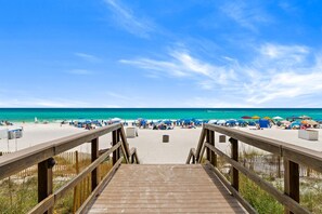 A wooden boardwalk leading to a beach with umbrellas and beach chairs. - Beachfront Bliss with Gulf Views and Resort Pools (Panama City Beach)