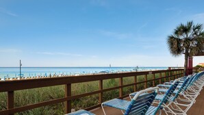 A beachside deck with rows of blue and white lounge chairs facing the ocean. - Beachfront Bliss with Gulf Views and Resort Pools (Panama City Beach)