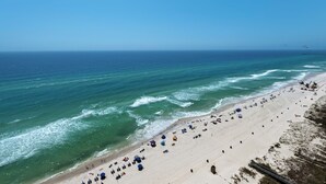 A beach with clear skies, calm sea, and a sandy shore with umbrellas and beach chairs. - Beachfront Bliss with Gulf Views and Resort Pools (Panama City Beach)