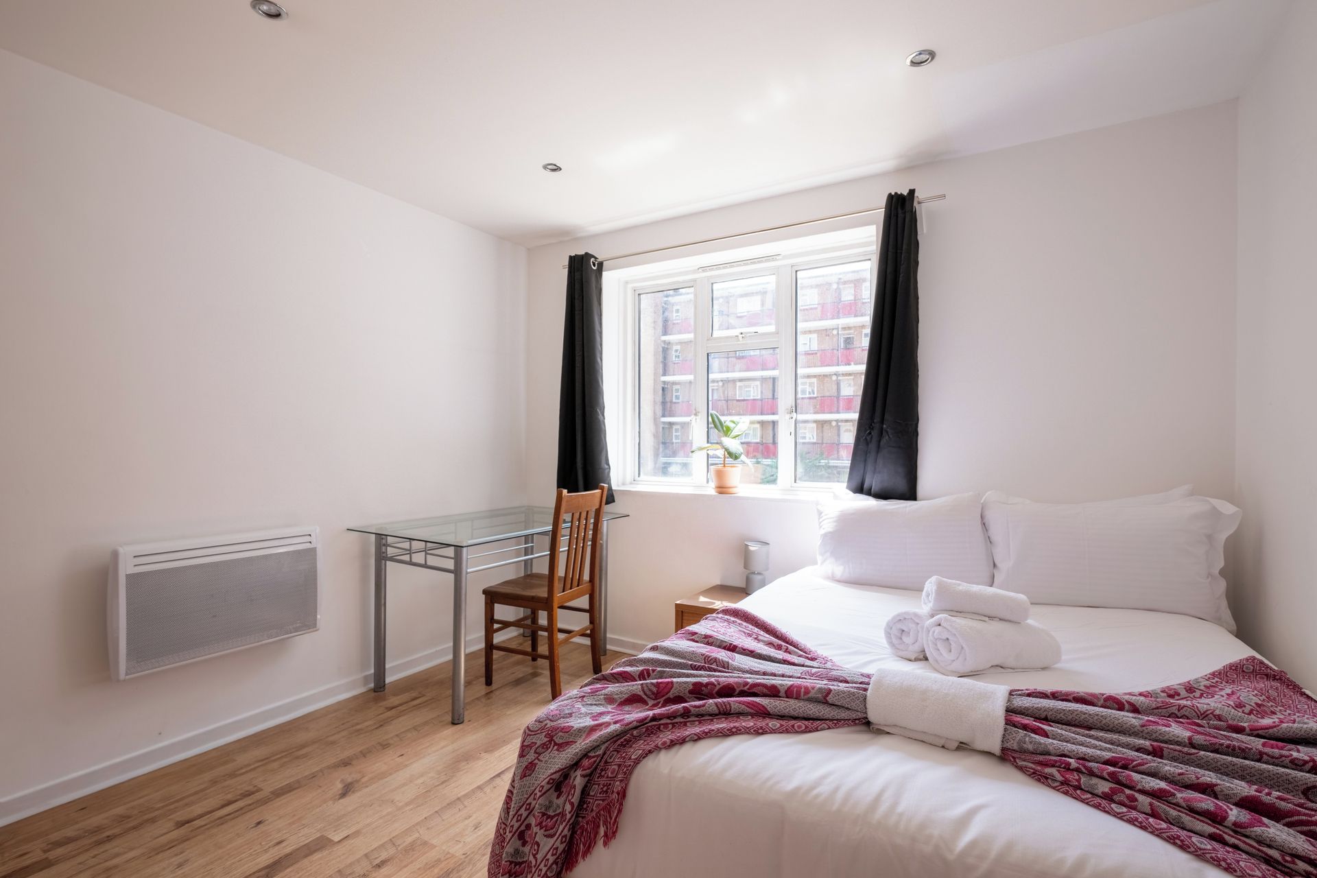 A hotel room with a bed, a desk, and a window with curtains.