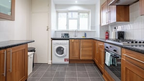 Een kleine keuken met een wasmachine, een fornuis en een spoelbak.