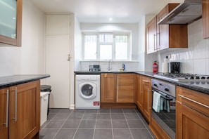 A compact kitchen with a washing machine, a stove, and a sink. - Spacious 3BDR Flat Near the Tower of London (Greater London)