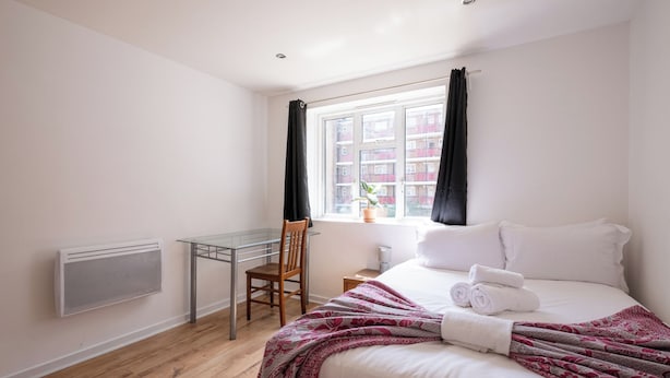 Een hotelkamer met een bed, een bureau en een raam met gordijnen.