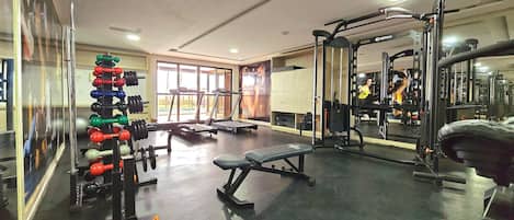 Un gimnasio con cintas de correr, máquinas de pesas y pesas sueltas.