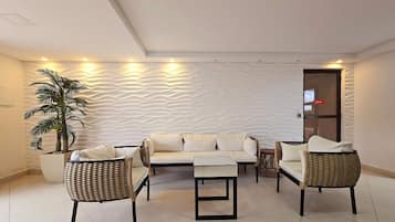 A modern living room with a sofa set, two armchairs, and a coffee table. There is a potted plant and a textured wall.
