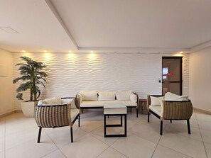 A modern living room with a sofa set, two armchairs, and a coffee table. There is a potted plant and a textured wall.