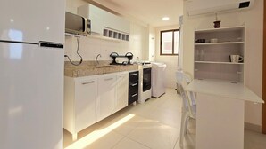 Una cocina moderna con muebles blancos, microondas integrado y estufa a gas.