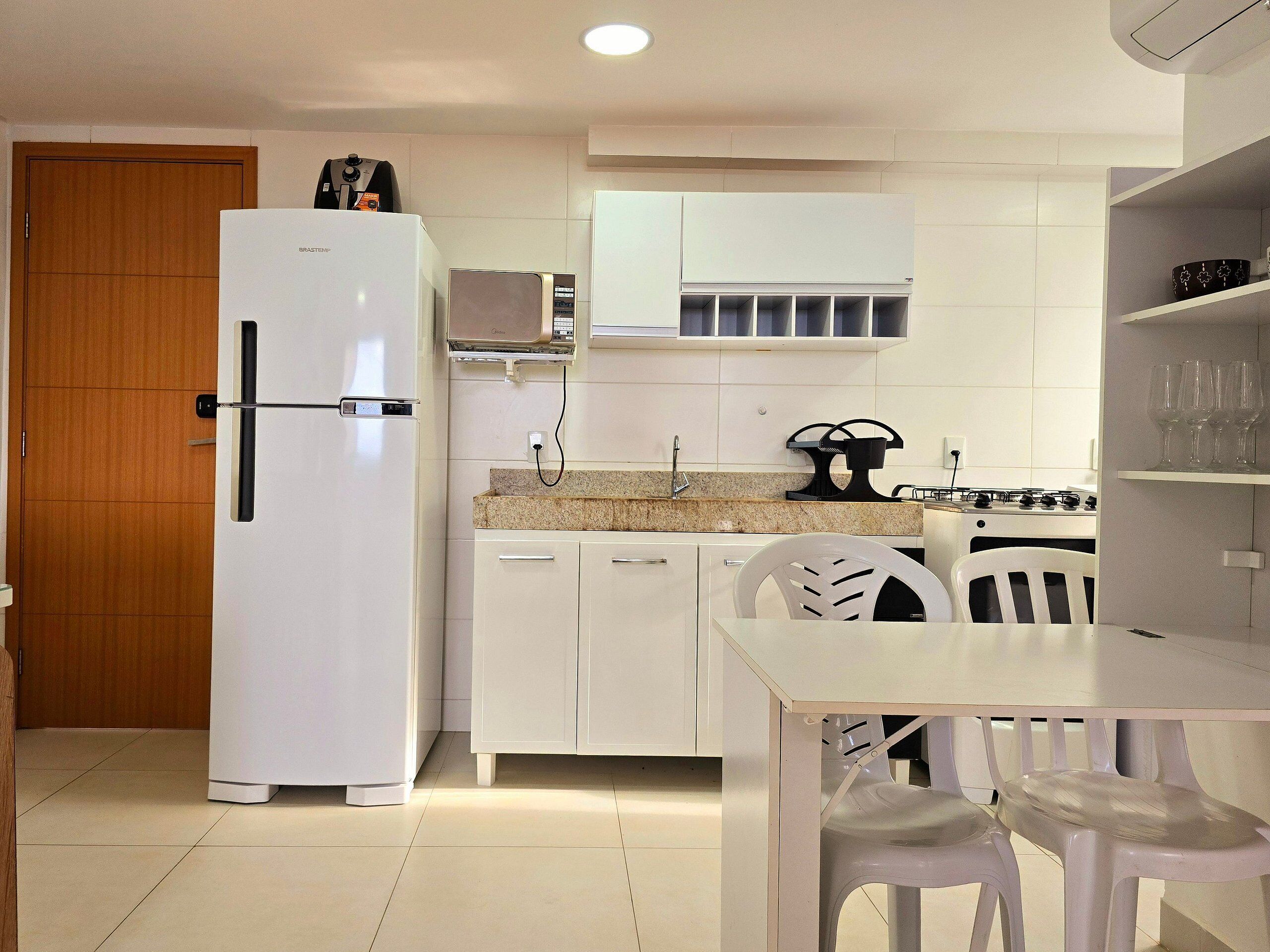 Una cocina compacta equipada con refrigerador, microondas y estufa a gas.